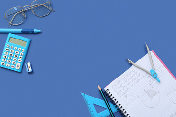 Notebook with eyeglasses, calculator and school stationery on blue background