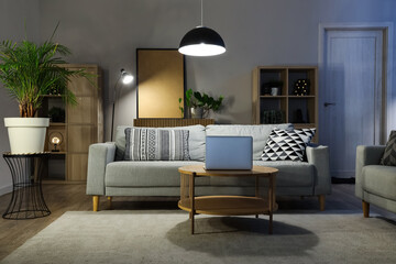 Interior of living room with comfortable sofa, table and glowing lamps