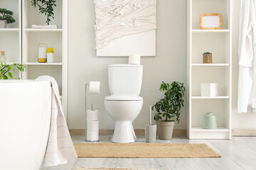 Interior of bathroom with toilet bowl, bathtub and shelving unit
