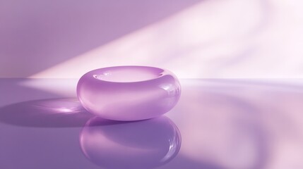 A purple glass bowl sits on a table, reflecting the light from a window