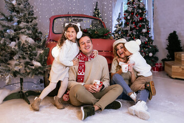 Parents and their children having fun sitting near red car