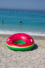 Obraz premium Borsh,Albania, July 10,2024: people enjoying the stone beach with crystal water and mat with watermelon, summer fun