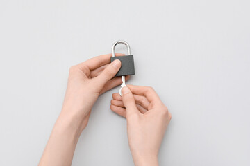 Hands with padlock and key on grey background