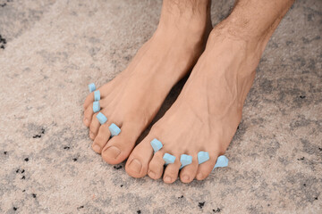 Feet of young man with toe separator and fresh pedicure at home, closeup