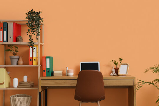 Comfortable workspace with modern laptop near orange wall