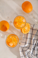 Glasses of Aperol spritz cocktail and oranges on white background