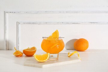 Glass of Aperol spritz cocktail and oranges on white wooden table
