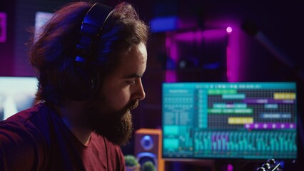 Professional songwriter playing guitar and using soundboard for mixing and mastering tracks....