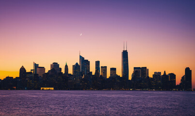 Obraz premium The Chicago skyline is silhouetted against a beautiful sunset, with the moon visible in the sky