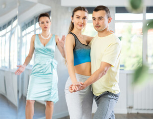 Guy and girl in sports clothes, under guidance of mentor, practice waltz in choreographic studio....