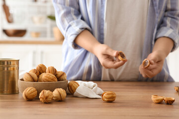 Woman with tasty walnut shaped cookies at wooden table at home