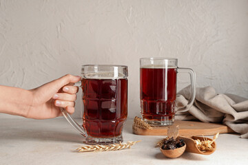 Female hand with glasses of fresh kvass on white background