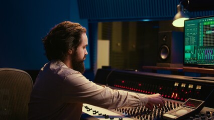Portrait of music producer working in control room professional studio and editing audio...