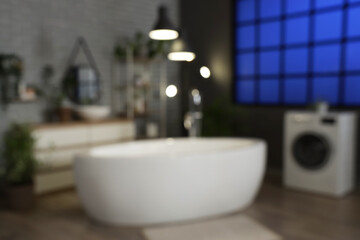 Blurred view of dark bathroom with bathtub, washing machine and glowing lamps in evening