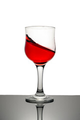 Red wine splashing in glass against white background. Copy space.