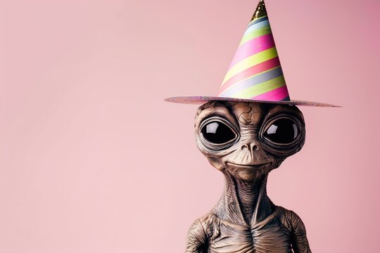portrait alien ufo with big black eyes in festive party hat on light pink background. Birthday celebration concept
