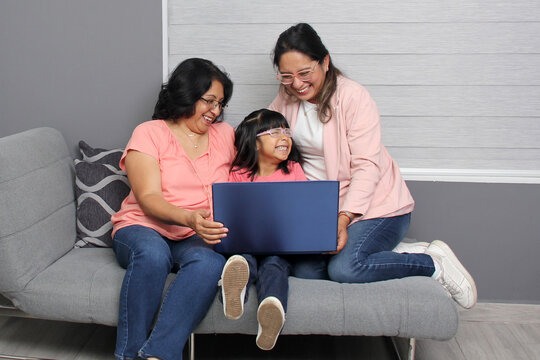 Three generations brunette latina grandmother, mom and daughter with glasses are surprised and excited while using laptop to shop with discounts and promotions