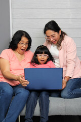 Fototapeta premium Three generations brunette latina grandmother, mom and daughter with glasses are surprised and excited while using laptop to shop with discounts and promotions
