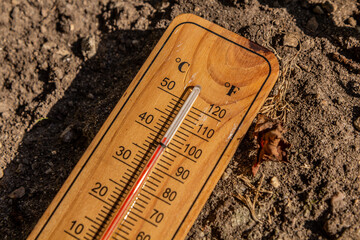 Thermometer displaying high summer temperature on a dry dirt background