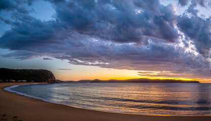 Sunrise over the ocean with clouds and a calm sea