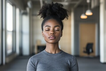 A young woman practices deep breathing exercises in a bright office during midday, focusing on stress management and relaxation techniques.