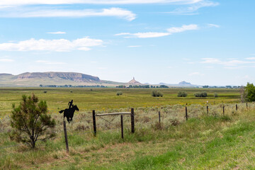 A horse shaped sign stands near a barbed wire fence on a sunny day in the Nebraska countryside with...