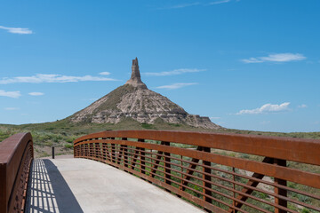 View of Chimney Rock from the bridge on a sunny day in Nebraska with clear blue skies and a hint of...