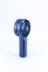 Small navy blue fan isolated on white background. Portable rechargeable mini fans. Close-up.