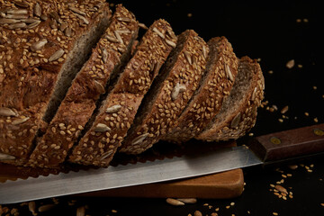 Artisanal bread made and baked at home with multigrain seeds on a dark background, a healthy...