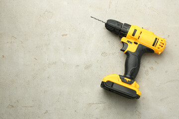Modern cordless electric drill on light grey table, top view. Space for text