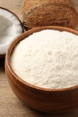 Coconut flour in bowl and fresh fruits on table, closeup