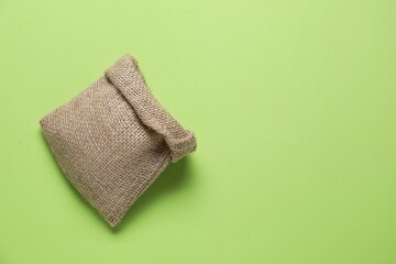 One burlap sack on light green background, top view. Space for text