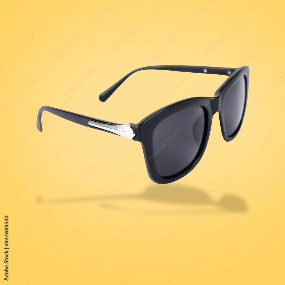 Wall mural Stylish sunglasses in air on yellow background