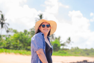 A joyful woman in her 60s enjoying a sunny beach day, feeling confident and beautiful, challenging aging stereotypes. The background features a beach with coconut trees.