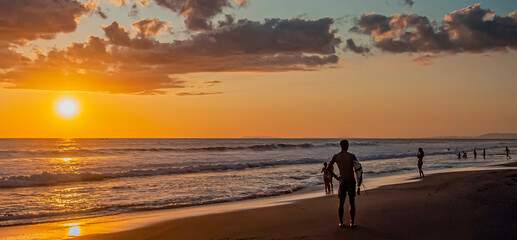 Unknown man with surfboard on the beach at sunset