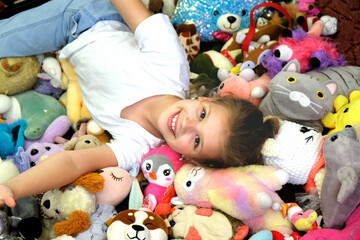 Pile of toys, heap of multicolored stuffed toys. Happy smiling girl enjoying with toys. Happy Birthday.