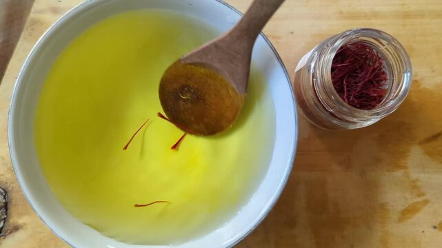 Top view of herbal cup on the table. A wooden spoon mixing crimson saffron stripes actively. healthy drink inspiring and delicious.