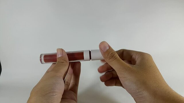 Close up shot of shiny pink lipstick, woman's hand is closing the lipstick by twisting it and ready to store.