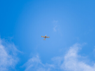 Small ultralight airplane with overhead wing and single propeller flying in sunset sky.