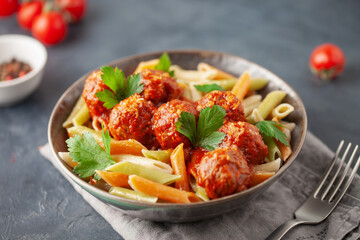 Penne pasta with veggie balls in tomato sauce and vegetables in a bowl. Vegetarian food