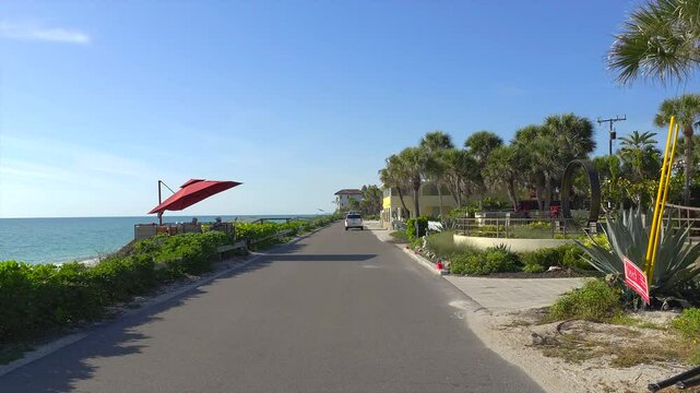 Car point of view driving on scenic road in sunny Florida. Casey Key coastal residential community picturesque streets.