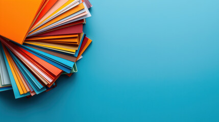 Stack of multicolored paper sheets fanned out on a bright blue background, perfect for creative and office-related themes.