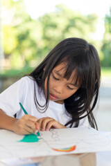 A young girl is drawing on a piece of paper with a marker.