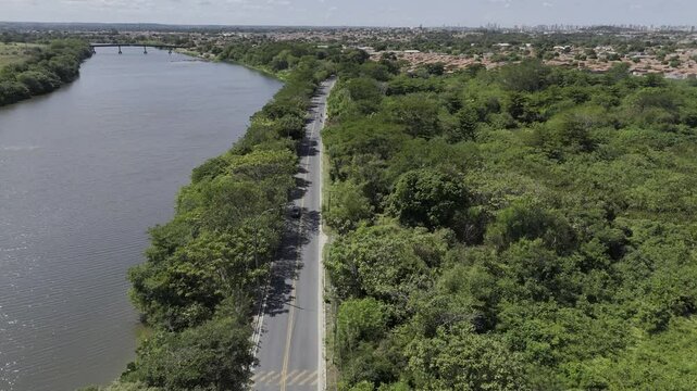 Drone follows highway along Poti River surround by trees, with motorcycles speeding through in Teresina, Piau&iacute;, Brazil