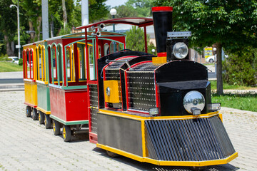 Children train and locomotive in an amusement park on a summer day