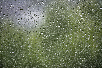 Window surface covered with many water droplets of various sizes, creating a textured pattern