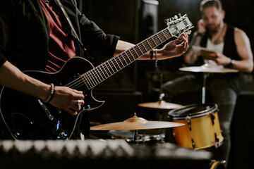 Unrecognizable rock musician playing in band preparing for performance tuning electric guitar, copy...