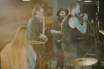 Group of gen X heavy metal musicians enjoying being on stage in modern nightclub, copy space