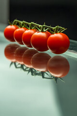 A cluster of cherry tomatoes balanced on the edge of mirror table