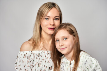 Portrait of young mother and daughter. Happy woman with child girl. Family portrait on a white...